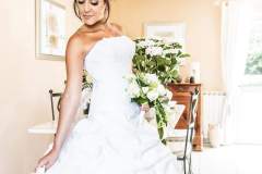 future mariée souriante fin prête chez elle en robe blanche avec son bouquet blanc