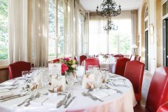 tables de mariage dressées avec fauteuils en cuir rouge dans la véranda du château des Comtes de Challes