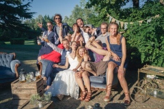 couple de jeunes mariés et leurs amis faisant des grimaces sur une banquette dans le parc du château de leur mariage