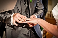 main du marié passant l'alliance au doigt de son épouse à l'église