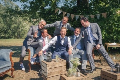 marié et ses amis souriant sur une banquette dans le parc du château de son mariage