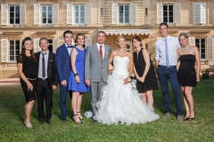 couple de mariés entouré des témoins souriant en prenant la pose dans le parc du château de leur mariage