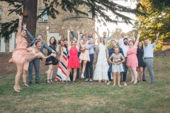 photo de groupe des amis des mariés tous bras en l'air dans le parc du château de leur mariage