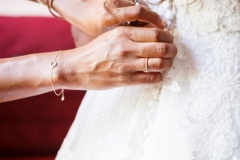deux mains attachant les boutons dans le dos de la robe de la mariée
