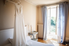 robe de mariée blanche suspendue au dessus du lit de la chambre des mariés