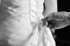 main attachant les lacets dans le dos d'une robe de mariée