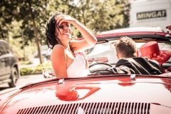 sourire d'une mariée cheveux au vent à l'arrière d'un cabriolet Renault vintage en roulant dans les rues de Lyon