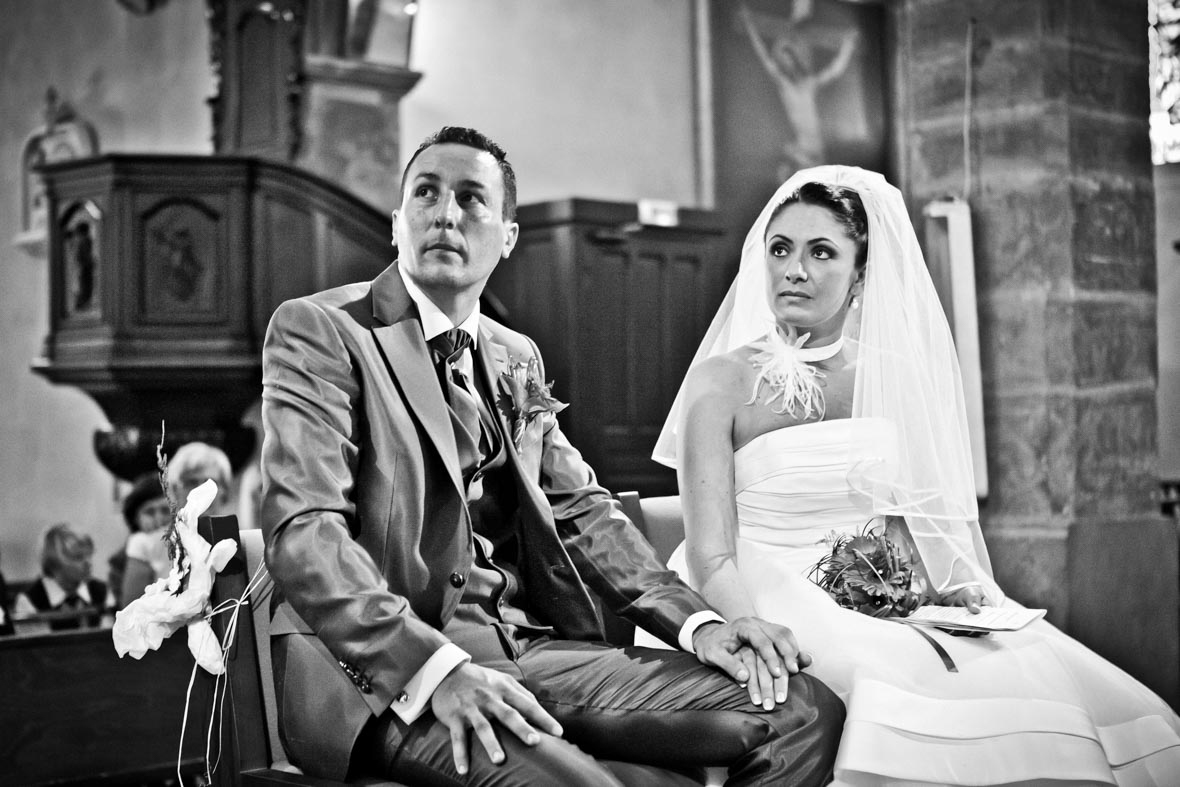 image type cinéma en noir et blanc de mariés se tenant par la main pendant la cérémonie religieuse