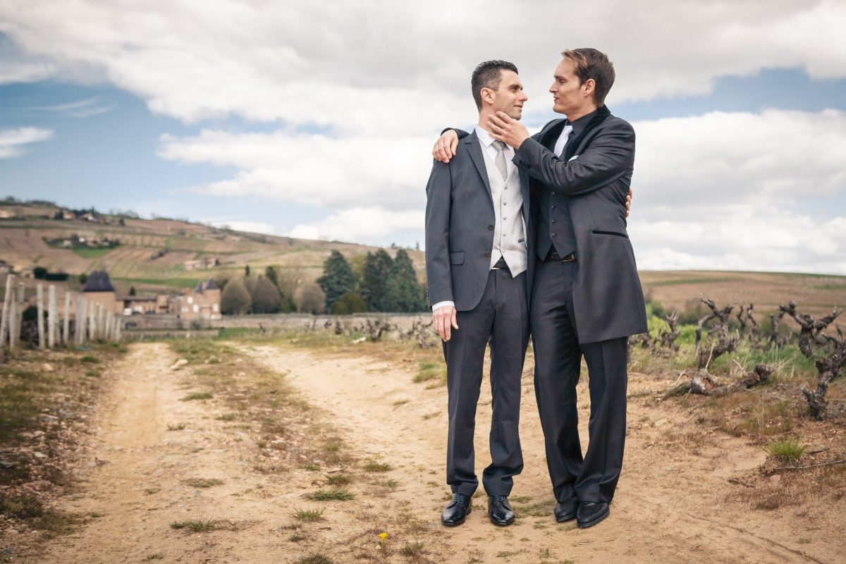 photo en couleur de couple d'hommes tout juste mariés posant dans une vigne du beaujolais
